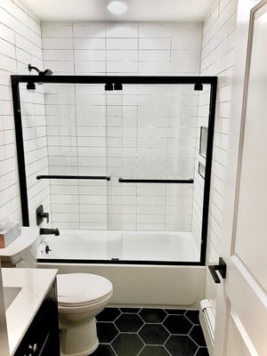  Bathroom with white subway tile and black hexagon tile flooring.